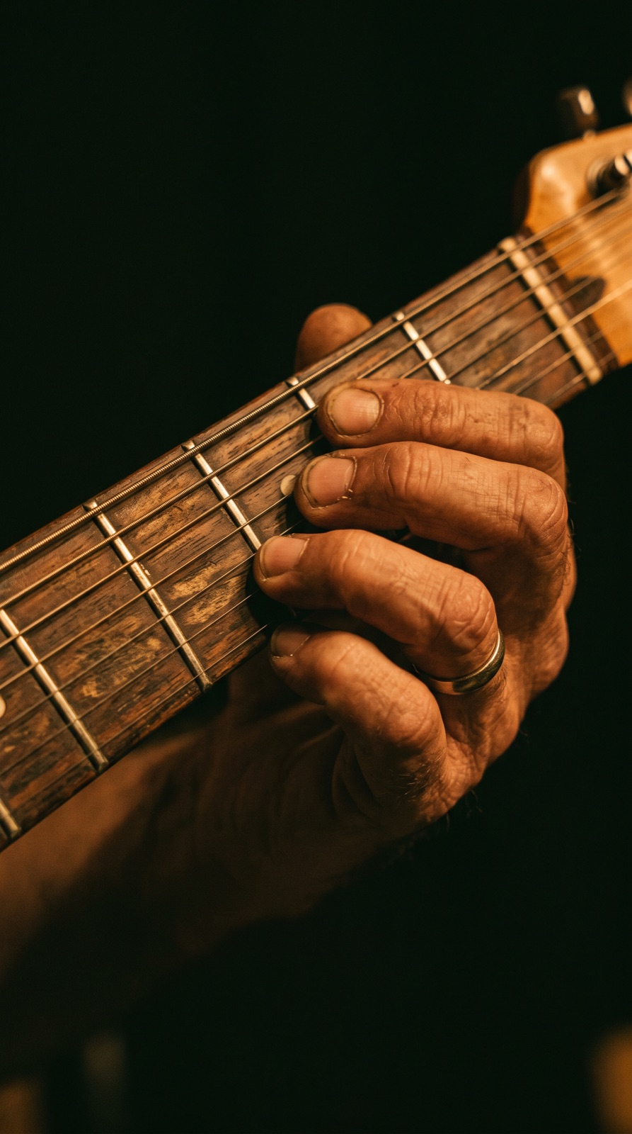 Hands playing a chord on a guitar fretboard